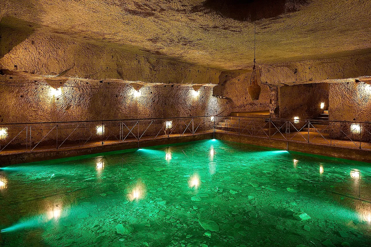 Una cisterna rinascimentale con acqua verde illuminata nella Galleria Borbonica di Napoli