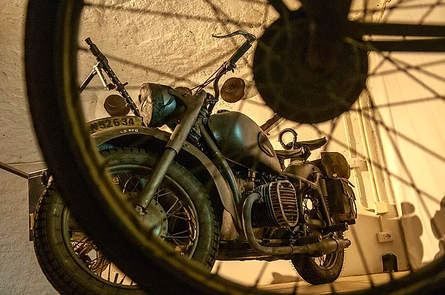 Ein Motorrad aus den 1940er-Jahren, hinter einem Speichenrad ausgestellt, in der Galleria Borbonica, Neapel