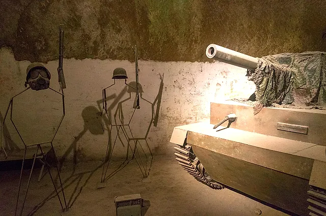 Eine Kriegsausstellung mit einem Panzer und Soldatensilhouetten in einer Tuffhöhle im unterirdischen Neapel